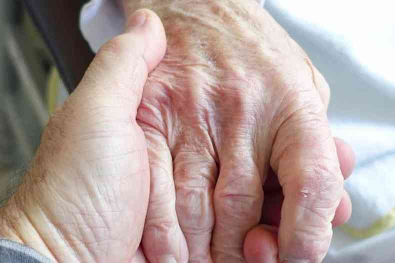 Pessoa dando a mão a um idoso
