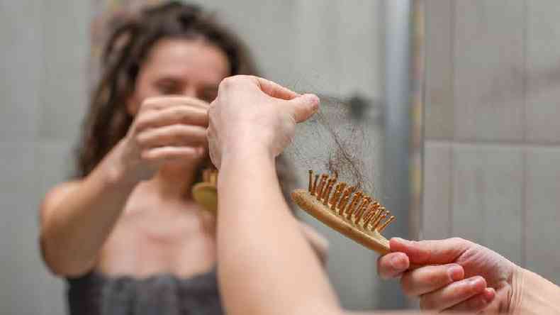 Mulher com escova cheia de cabelo