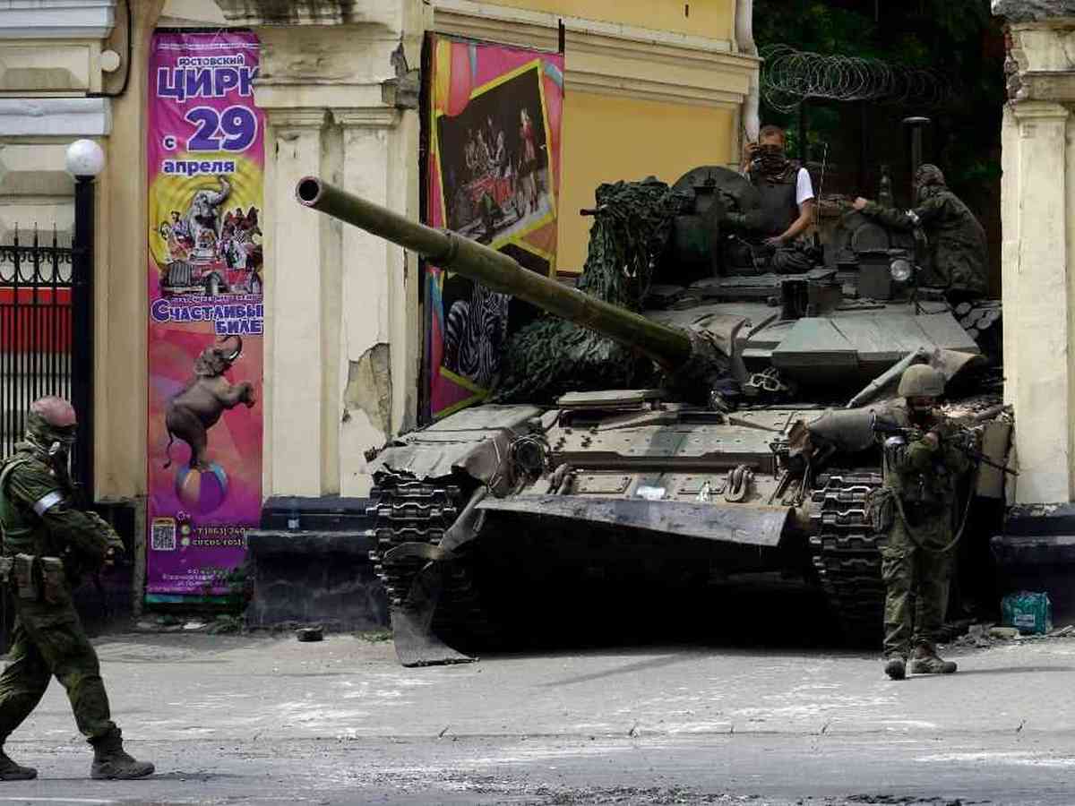 Uma mulher soldado servindo no exército está perto de um tanque de batalha