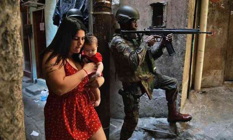 Mulher com beb ao colo passa prximo de soldado na Rocinha, no Rio de Janeiro(foto: CARL DE SOUZA / AFP)