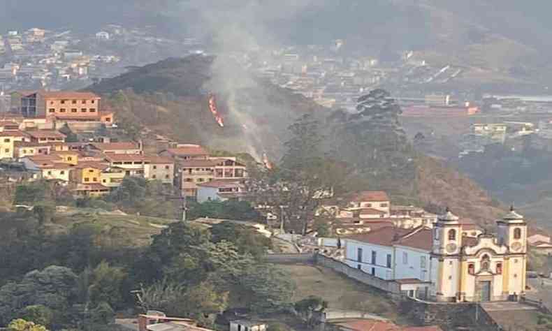 Vista de longe mostra foco de incêndio próximo a igreja e casas antigas de Mariana