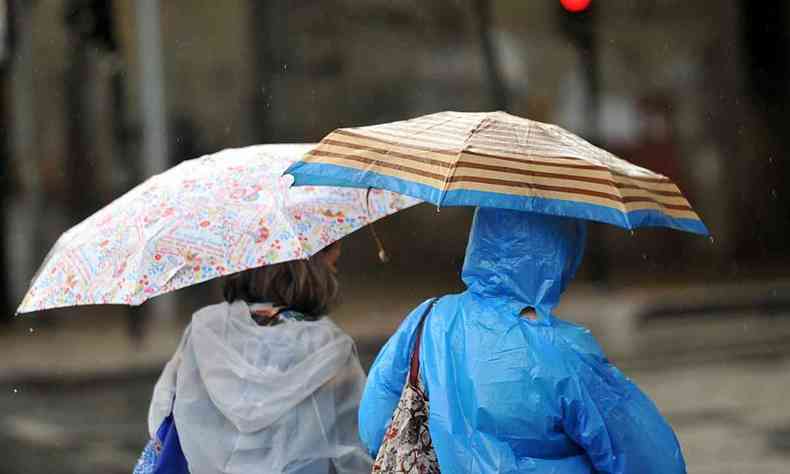 pessoas com capa e sombrinha para se proteger da chuva em BH