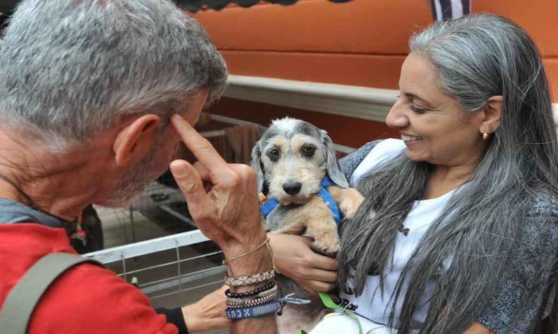 Imagem mostra Jane segurando uma cachorrinho, enquanto conversa com um tutor interessado na adoo