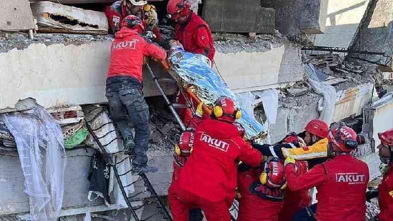 Equipes de resgate carregam uma mulher resgatada de um prdio que desabou aps um terremoto em Kahramanmaras, na Turquia