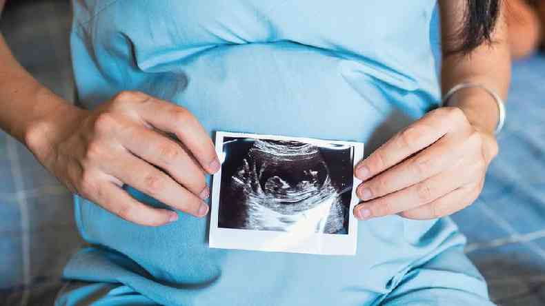 Uma mulher segurando a ultrassonografia do beb