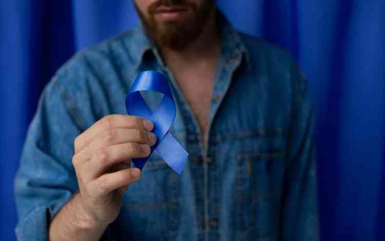 Homem segurando lao azul em conscientizao ao cncer de prstata 