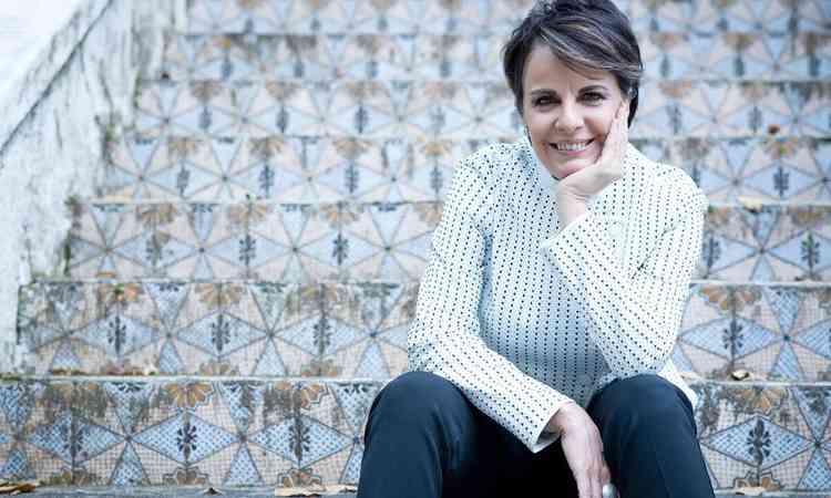 Cantora Leila Pinheiro est sentada em escada de azulejos e sorri