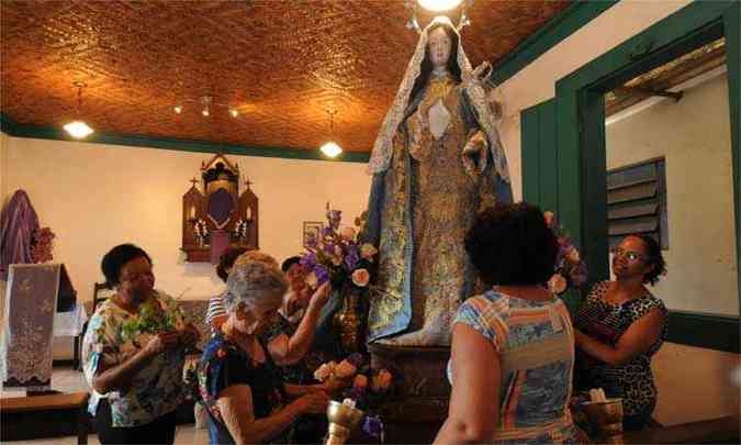 Antes de partirem para a tradicional procisso do encontro, mulheres adornam a imagem de Nossa Senhora das Dores com rosas(foto: Cristina Horta / EM / D.A Press )