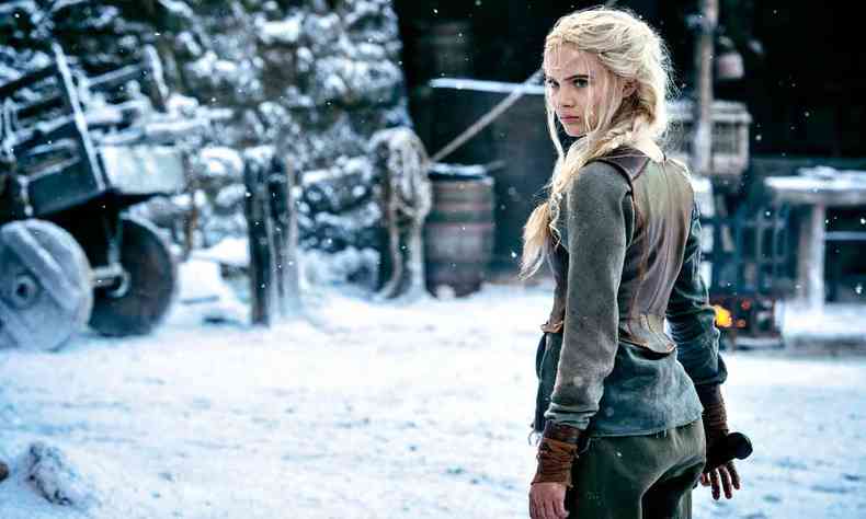 Atriz Freya Allan olha para trás, em cenário coberto de neve, durante cena da série ''The witcher''