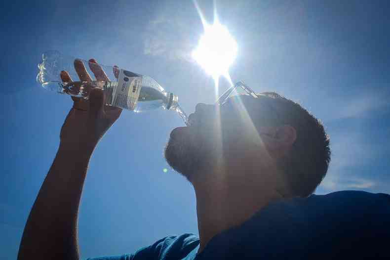 Homem bebendo gua debaixo de sol 