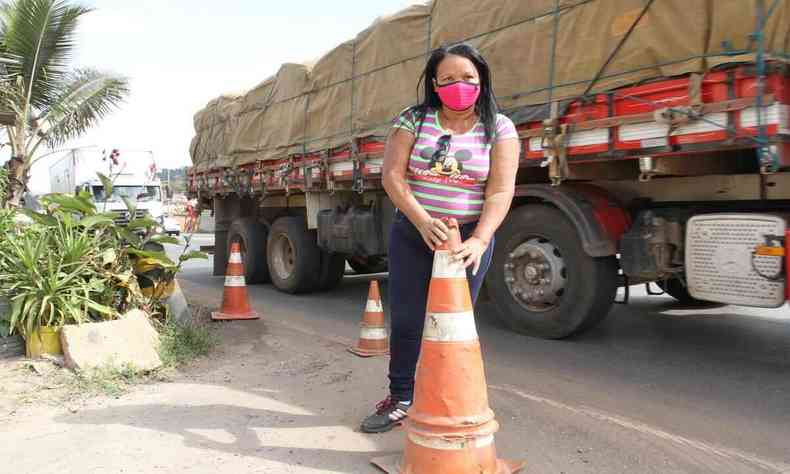 Imagem mostra Denilsa colocando cones na BR, ao fundo passa um caminho