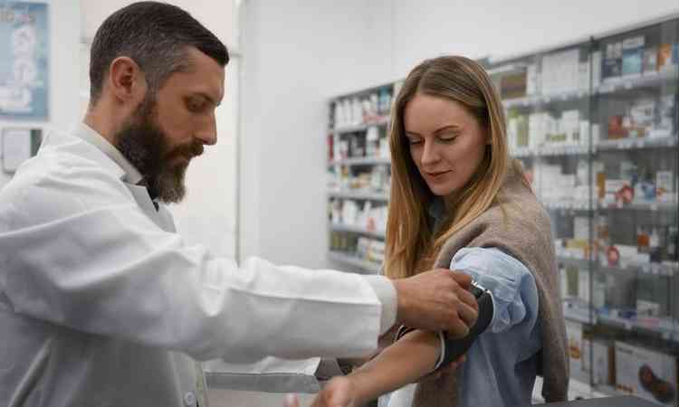 farmacutico masculino verificando a presso sangunea da mulher