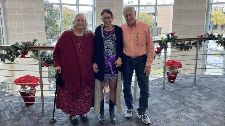 Registered as Melissa Highsmith, the woman changed her name to Melanie Walden after Elderly couple with younger woman in the middle; they smile continuously inside pr