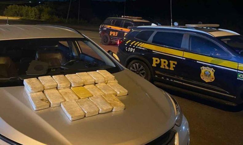 O carro, um Hyundai Santa Fé com placas de Mundo Novo (MS), era conduzido por uma mulher de 44 anos, quando foi interceptado no km 450 da rodovia(foto: PRF/Divulgação) Carro apreendido, com drogas em tabletes no capô do veículo. Viatura da PRF aparece do lado direto da imagem, vista de perfil