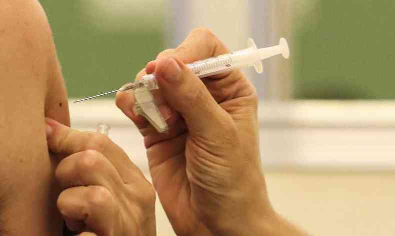 Braço recebe injeção de vacina 