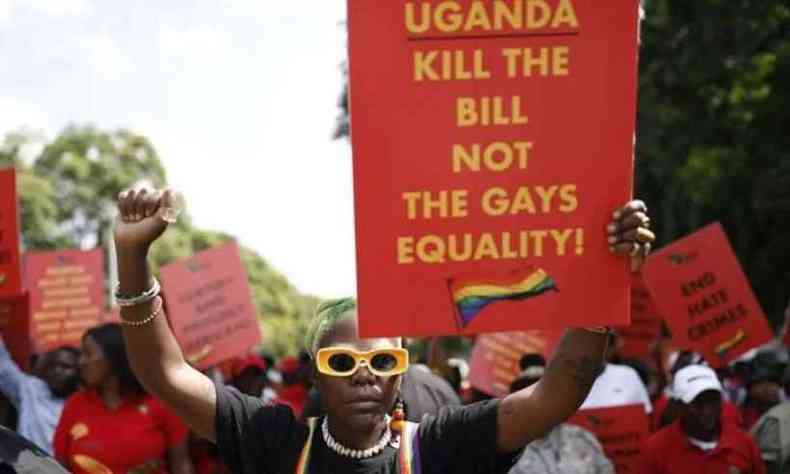 Uma pessoa negra com acessrios nas cores do arco-ris segura um cartaz no qual se l 'Uganda kill the bill not the gays equality'