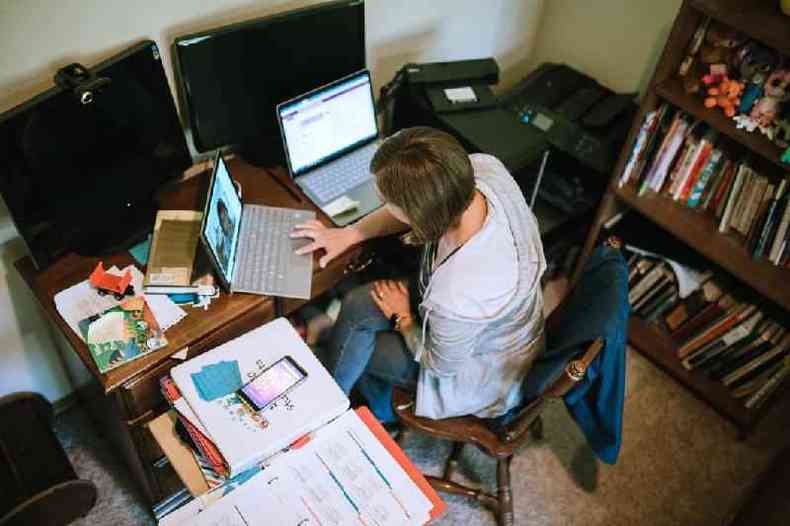 Mulher jovem trabalhando em casa com dois notebooks