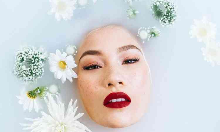 mulher imersa numa banheira com flores e gua branca, aparecendo somente o rosto