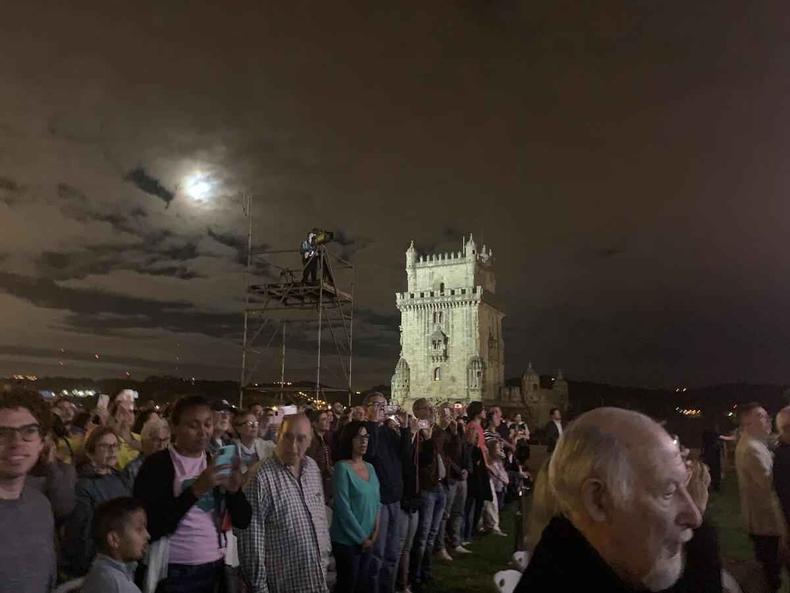 Grupo de pessoas assiste a concerto. Ao fundo est a Torre de Belm