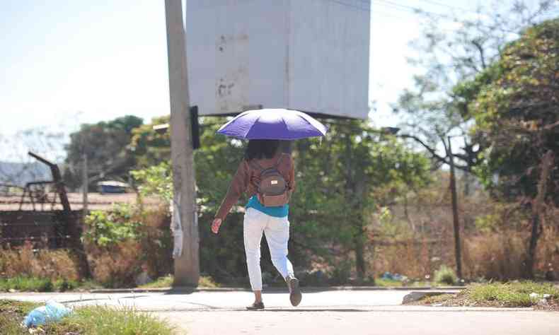 mulher andando numa rua segurando um guarda-chuva