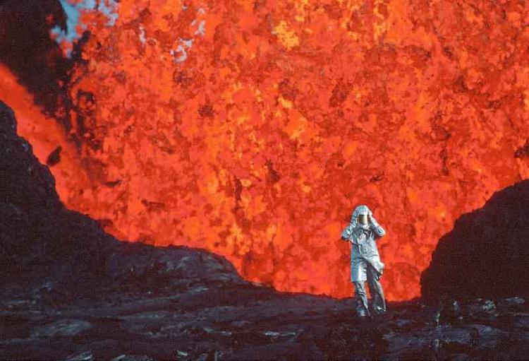 Katia Krafft aparece com roupa parecida com astronauta, na frente de lava vulcnica vermelha