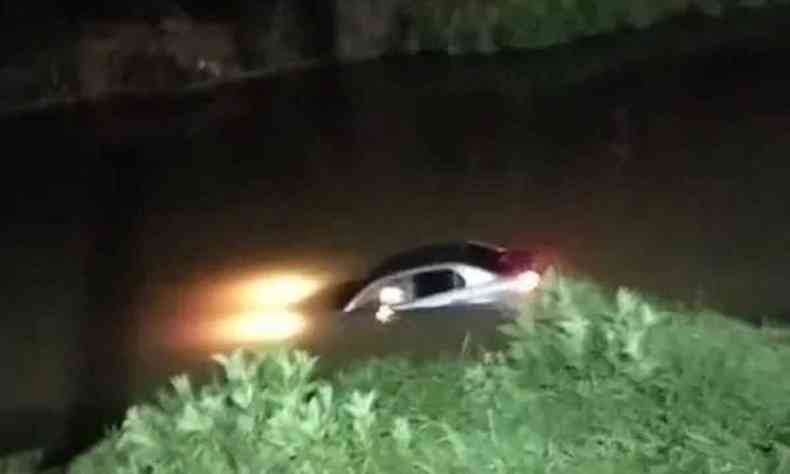 Na foto, carro parcialmente submerso em Rio Paraibuna