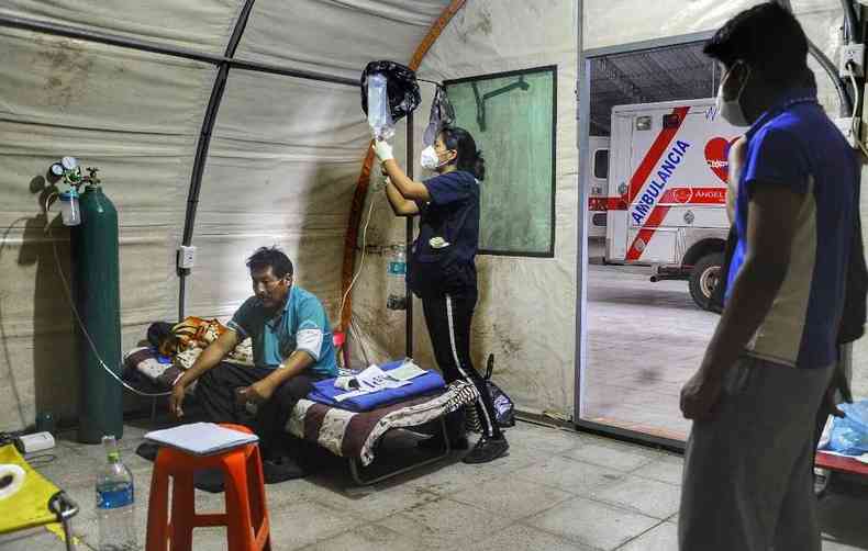 Imagem de paciente boliviano recebendo atendimento de voluntrios no combate  pandemia; ainda no h cura por medicamento confirmada pela medicina(foto: Enrique CANEDO / AFP)