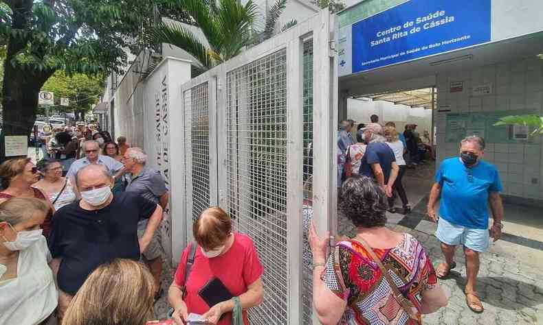 Fachada do Centro de Sade Santa Rita de Cssia, com algumas pessoas na porta esperando a sua dose da vacina, no Bairro So Pedro