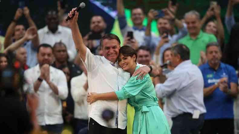 Jair Bolsonaro e Michelle Bolsonaro abraados em evento de campanha