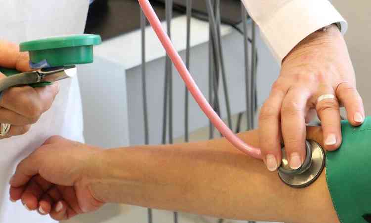 médico mede pressão arterial de uma paciente