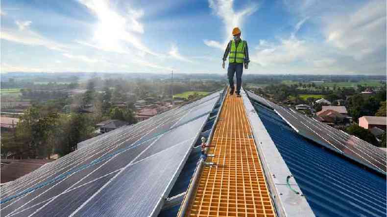 Homem caminha sobre placas de energia solar