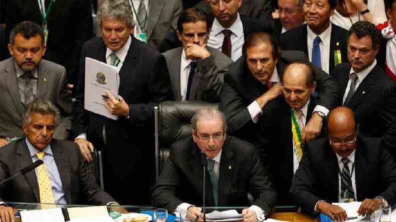 Eduardo Cunha na mesa da Cmara dos Deputados, rodeado por parlamentares homens