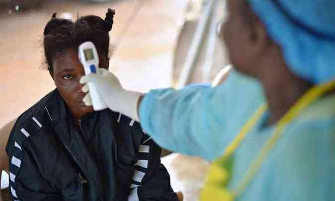 Garota com suspeita de ebola tem a temperatura aferida em hospital de Kenema, em Serra Leoa(foto: Carl de Souza/AFP )