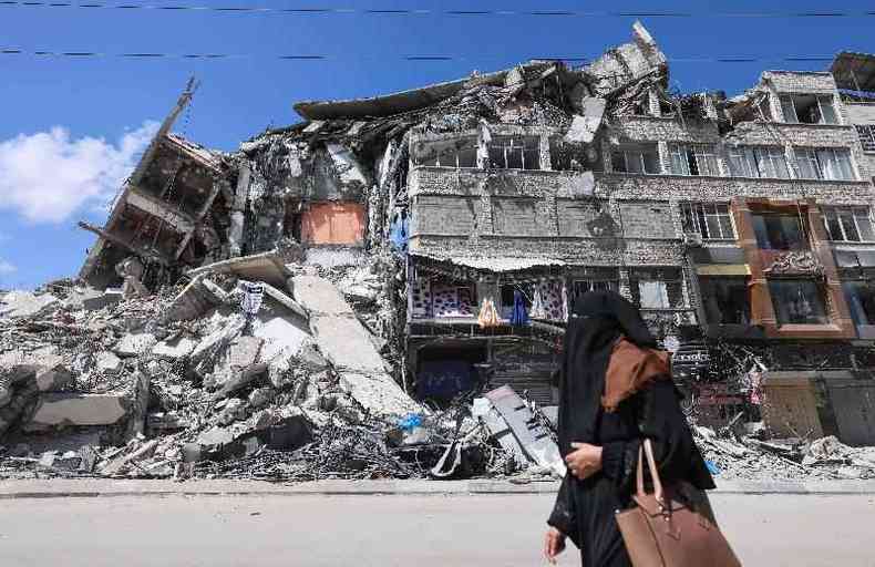 Mulher palestina passa em frente a prdio destrudo na cidade de Gaza(foto: EMMANUEL DUNAND/AFP)