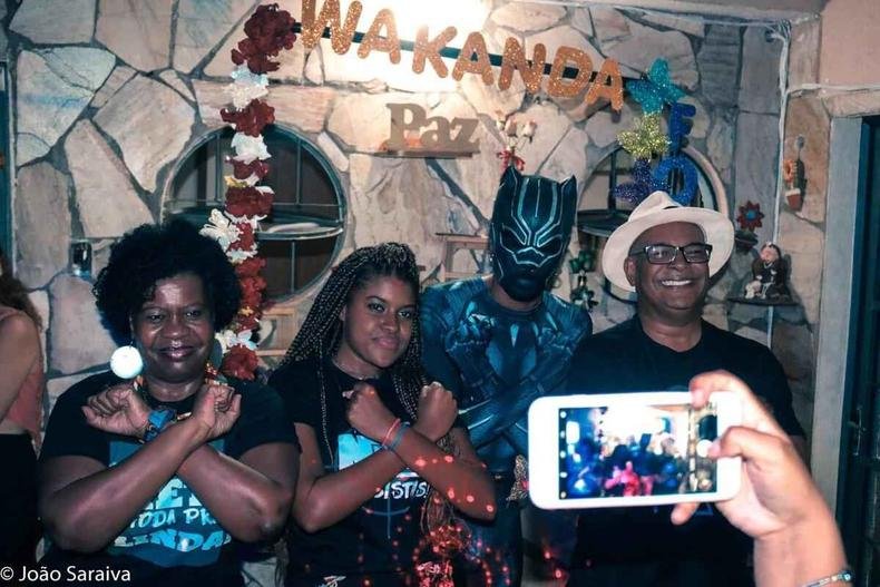 A professora Consola��o, Lu�sa Helena, 'Pantera Negra', e o pai Robertson Saraiva fazem o gesto de Wakanda, cruzando os bra�os