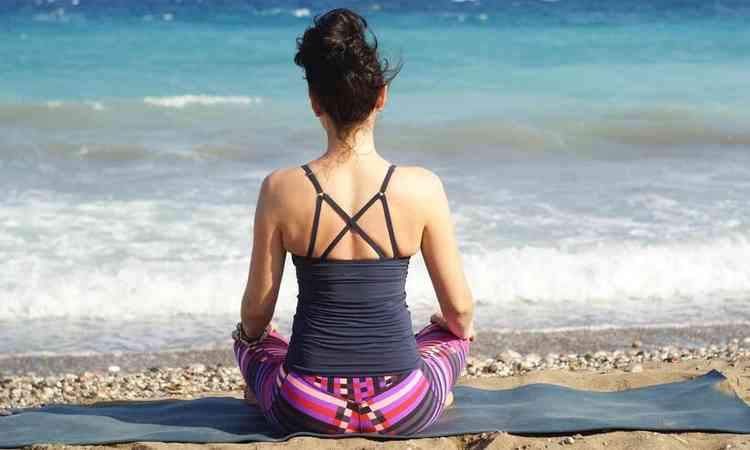 mulher meditando em frente ao mar