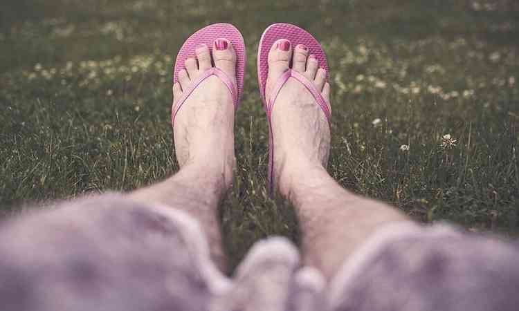 mulher de chinelo olha para as pernas, mas mostra apenas o tronco, sem o rosto