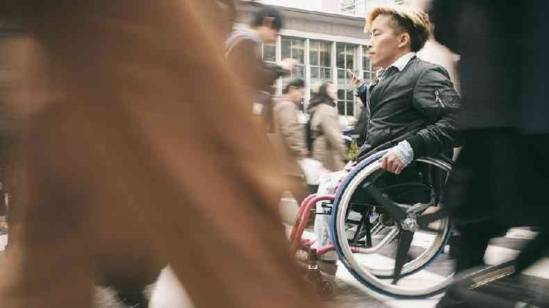 homem andando em cadeira de rodas na rua