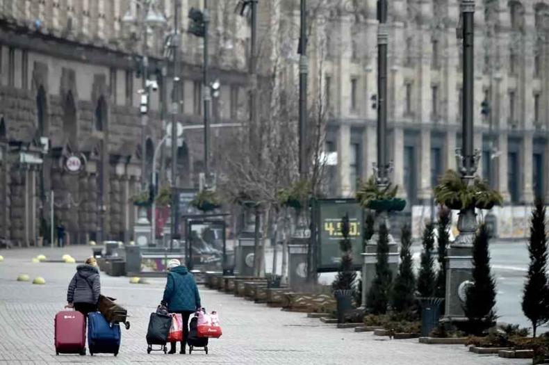 Mulheres carregam malas com seus pertences em uma rua deserta de Kiev, na Ucrnia, aps invaso russa