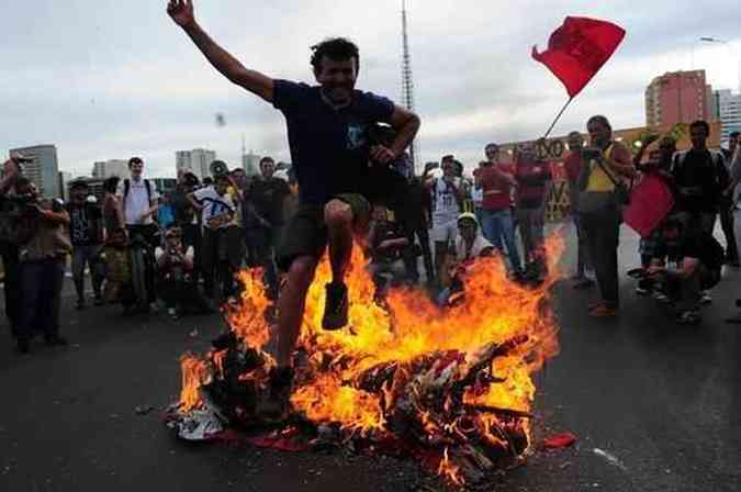 Manifestante pula rplica de papel da taa da Copa do Mundo, que foi queimada em protesto(foto: Bruno Peres/CB/D.A Press)