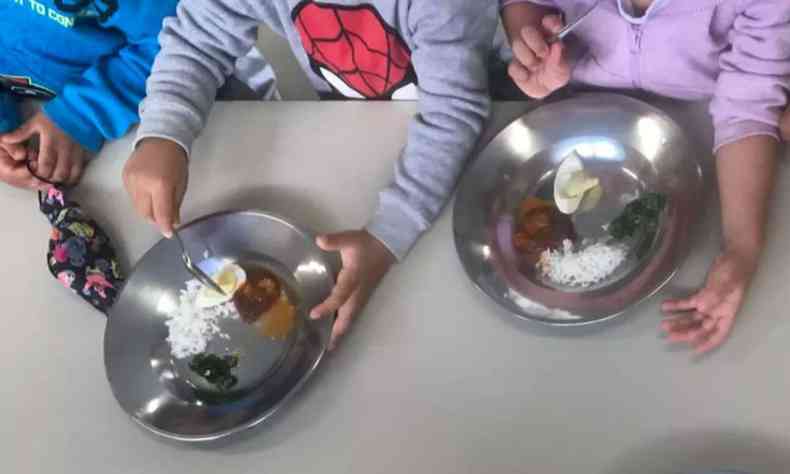 Foto de pratos dos alunos da EMEI com  de ovo e uma colher de arroz, sopa de verdura e molho de carne