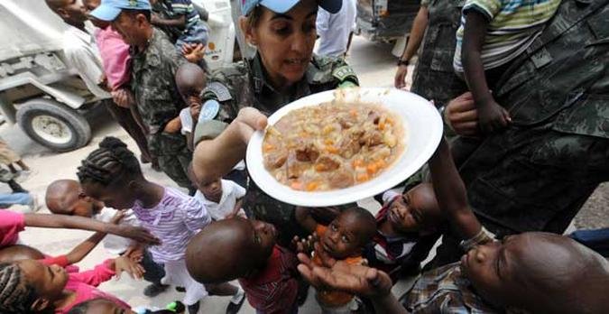 Soldado brasileiro alimenta crian�as haitianas(foto: VANDERLEI ALMEIDA / AFP)
