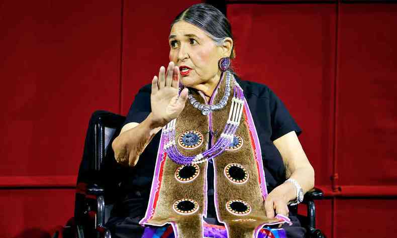 A atriz Sacheen Littlefeather no palco, vestida com trajes de sua etnia indgena, gesticula