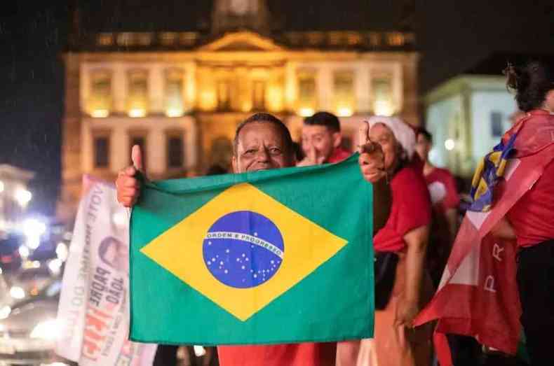 Eleitor com camisa vermelha e bandeira do Brasil nas mos comemora vitria de Lula/ ao fundo o Museu da Inconfidncia, iluminado