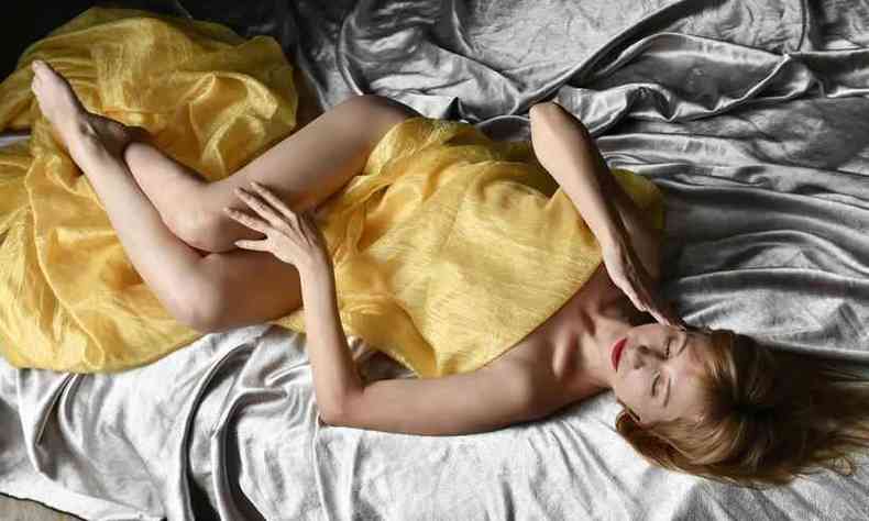 mulher deitada na cama, entre lenis