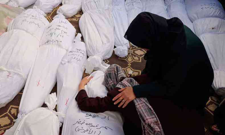 Mulheres choram diante de cadveres cobertos em Gaza