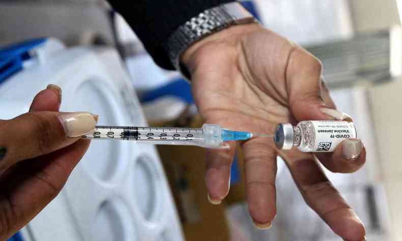 Imagem mostra mos de uma mulher segurana uma seringa, que contm a vacina triplice viral
