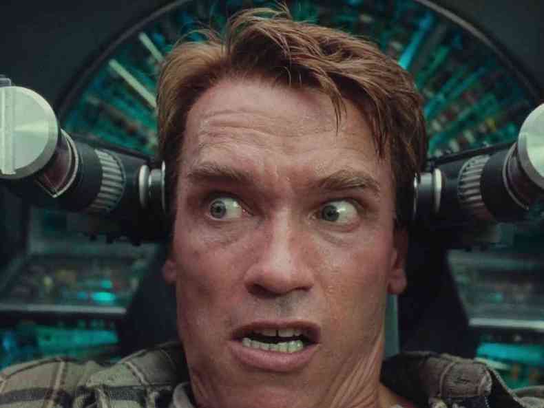 Arnold Schwarzenegger com expressão de dor no filme O vingador do futuro