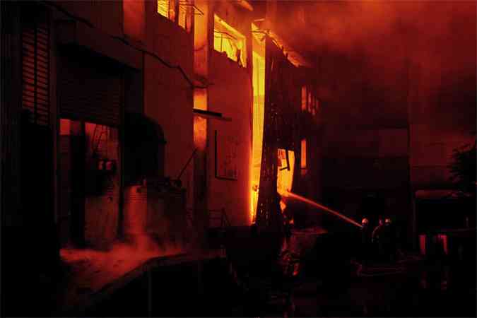 Os bombeiros tiveram trabalho para controlar as chamas e encontraram dezenas de corpos no interior do edifcio(foto: AFP PHOTO/Asif HASSAN )