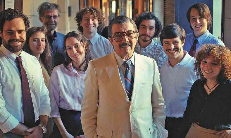 O ator Ricardo Darn, cercado de jovens atores, todos de p, sorri para a foto, em cena de Argentina, 1985